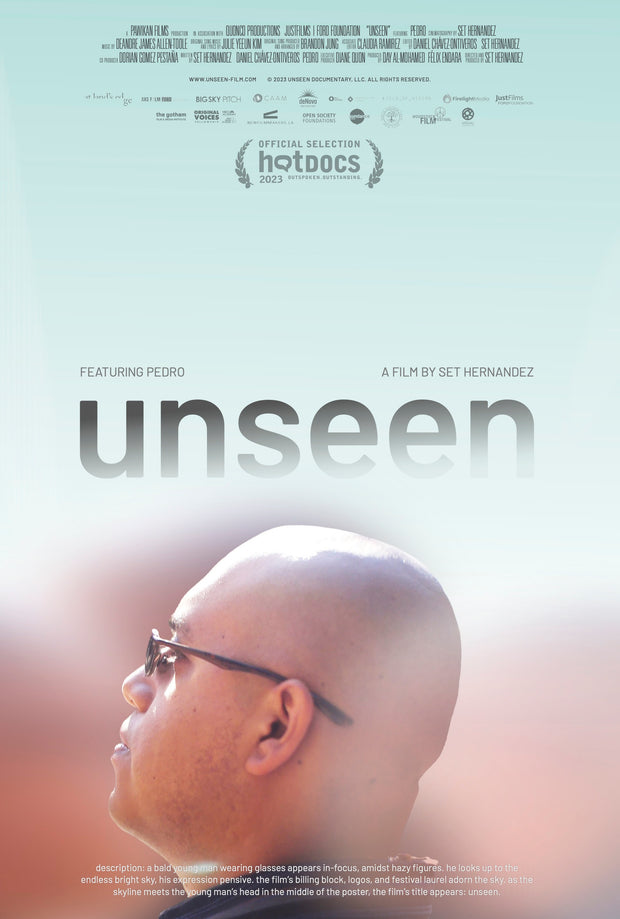 Film Poster for "UNSEEN". A bald young man wearing glasses appears in-focus, admist hazy figures. He looks up to the endless bright sky, his expression prensive. The film's billing black, logos, festival laurels adorn the sky as the skyline meets the young man's head in the middle of the poster. The film's title appears: unseen.