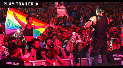 Trailer for documentary "Beirut Dreams In Color" directed by Michael Collins. Singer in concert facing audience with man holding up pride flag. https://vimeo.com/1054687437