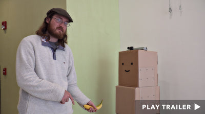 Trailer for documentary "Recovering Ruffin" directed by Katy Krauland and Kelby Wood. Man holding banana and standing next to boxes. https://vimeo.com/463977570
